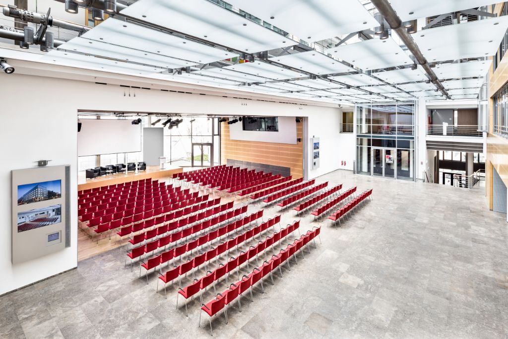 Blick von oben in den großen Saal des dbb forum, rote Stühle in Reihen aufgestellt