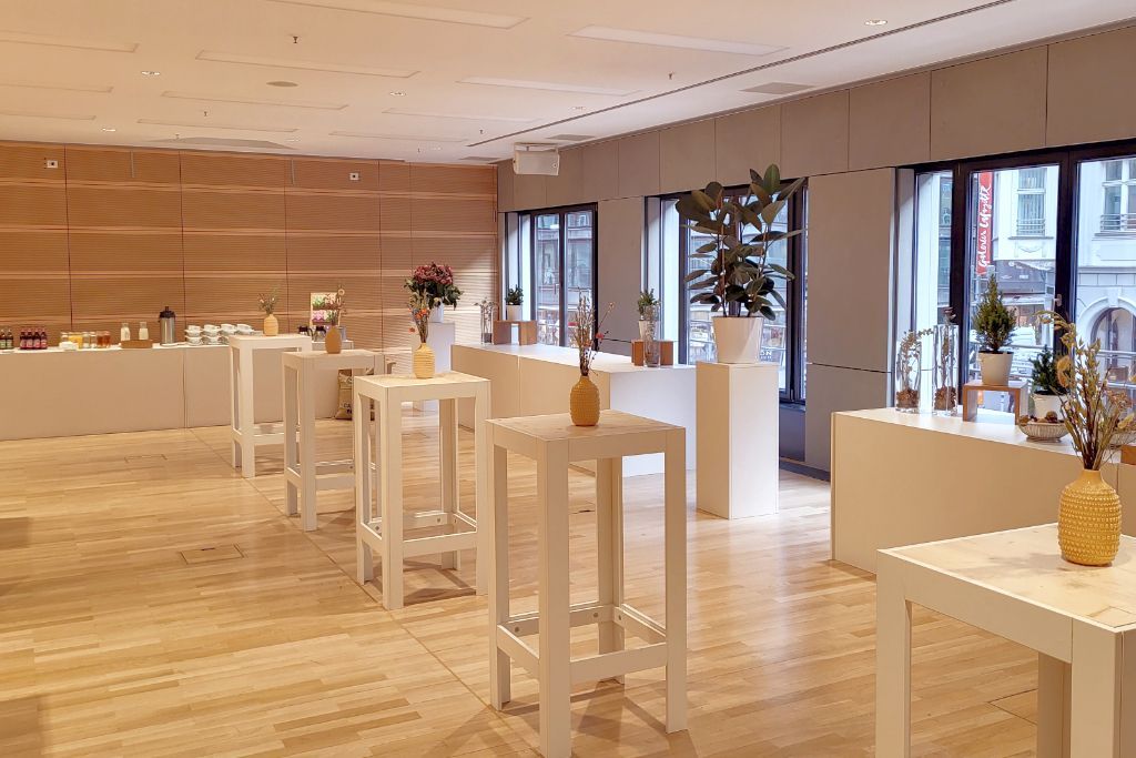 Kaffeepause im dbb forum. Weiße, quadratische Holzstehtische in der Mitte des Raumes, am Rnad Buffettische mit Getränken