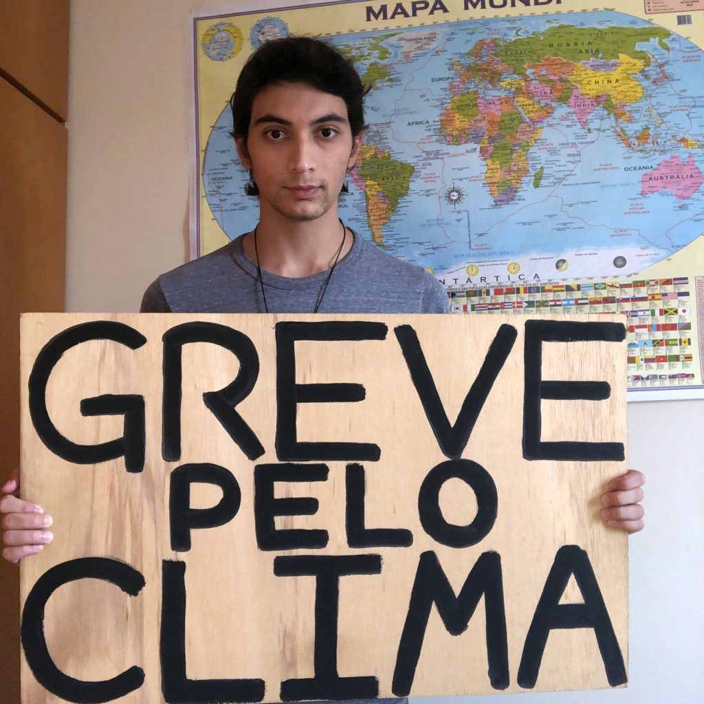 Estudante brasileiro participa de ato do Fridays for Future segurando cartaz em defesa do clima.
