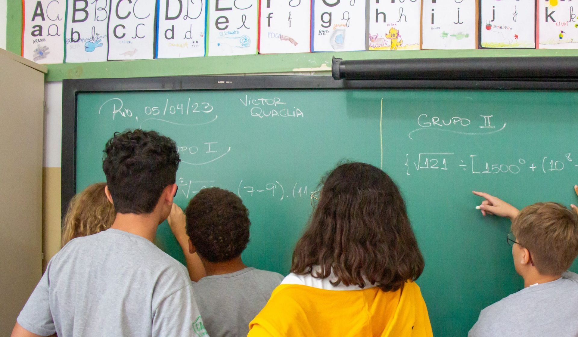 Grupo de alunos do ensino fundamental resolvendo equações matemáticas juntos.