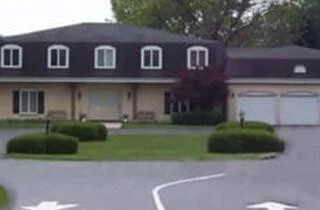 A large house with a black roof and white garage doors
