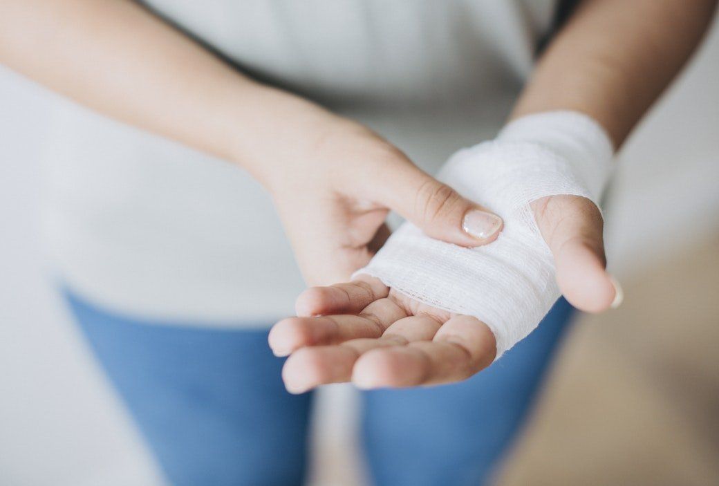 woman holding injured bandaged hand