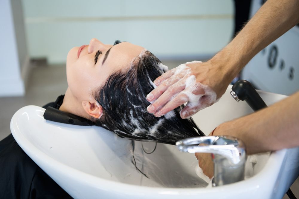 Hairdresser Washing a Client's Hair in a Salon Sink, With Shampoo Lather and Running Water — @miilan in Darwin City, NT