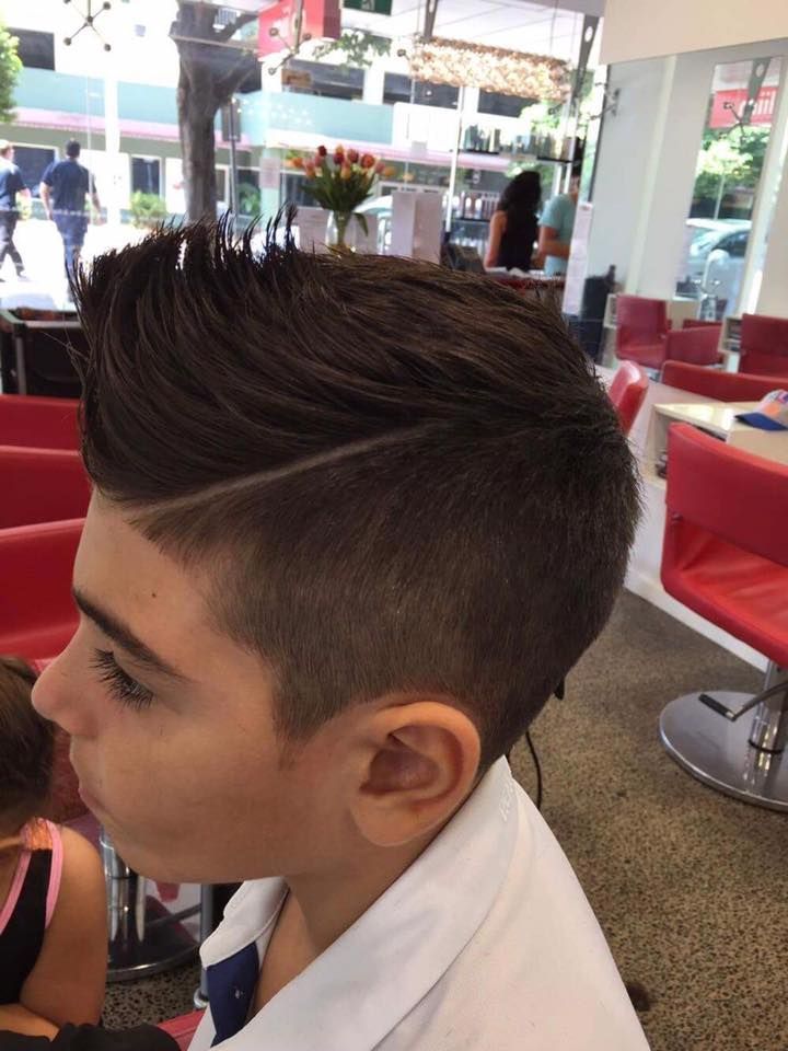 Stylist Cutting a Child’s Hair in a Bright Salon, With Other Customers Seated Nearby — @miilan in Darwin City, NT