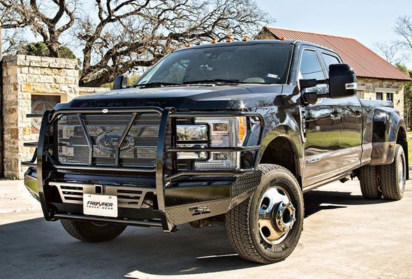 A black truck with a bumper grille is parked in front of a house.