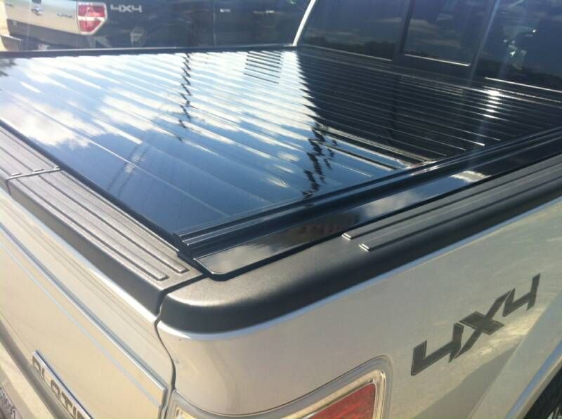 A white truck with a black bed cover on it