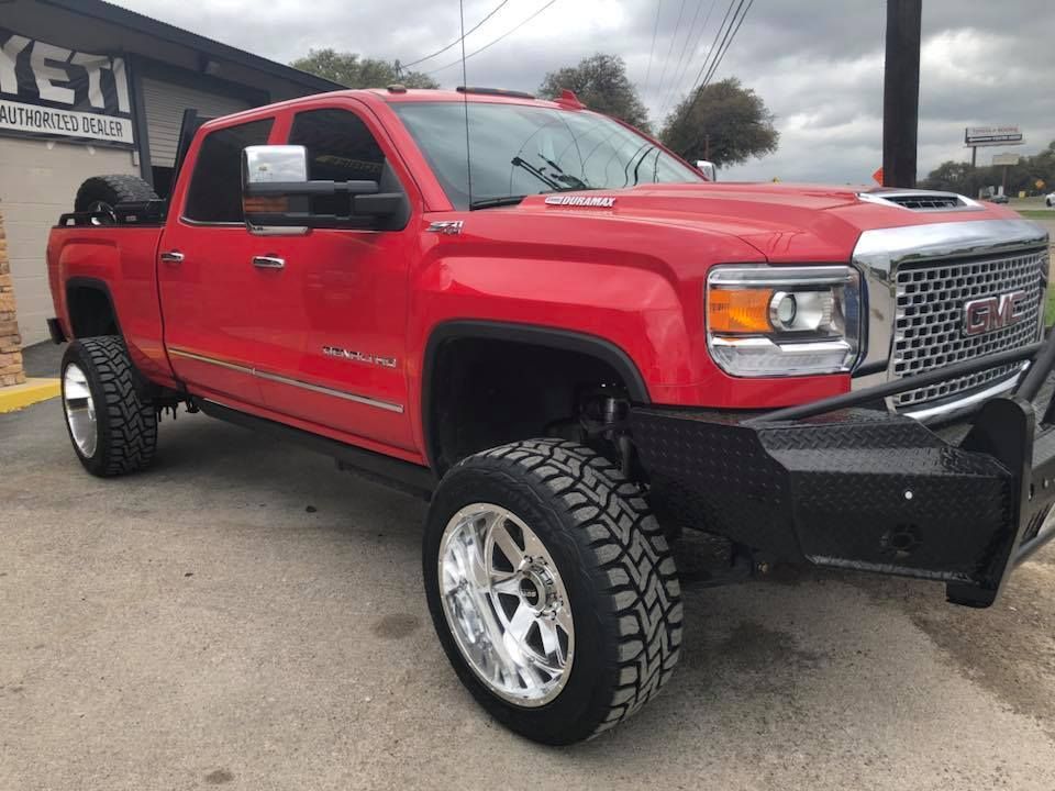 A red gmc truck is parked in a parking lot in front of a building.