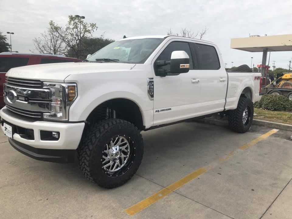 A white ford truck is parked in a parking lot.
