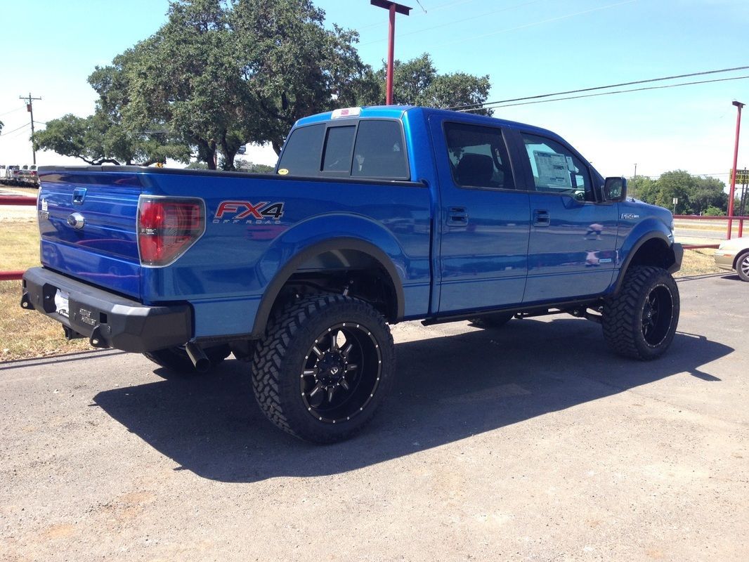 A blue truck is parked on the side of the road.