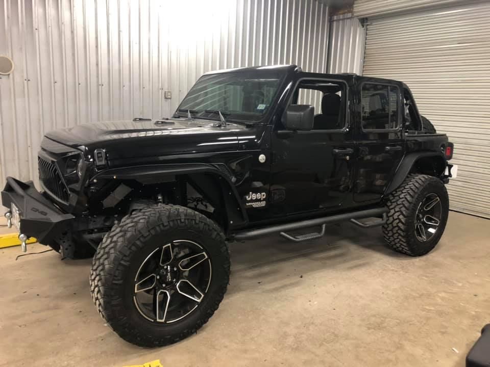 A black jeep wrangler is parked in a garage.