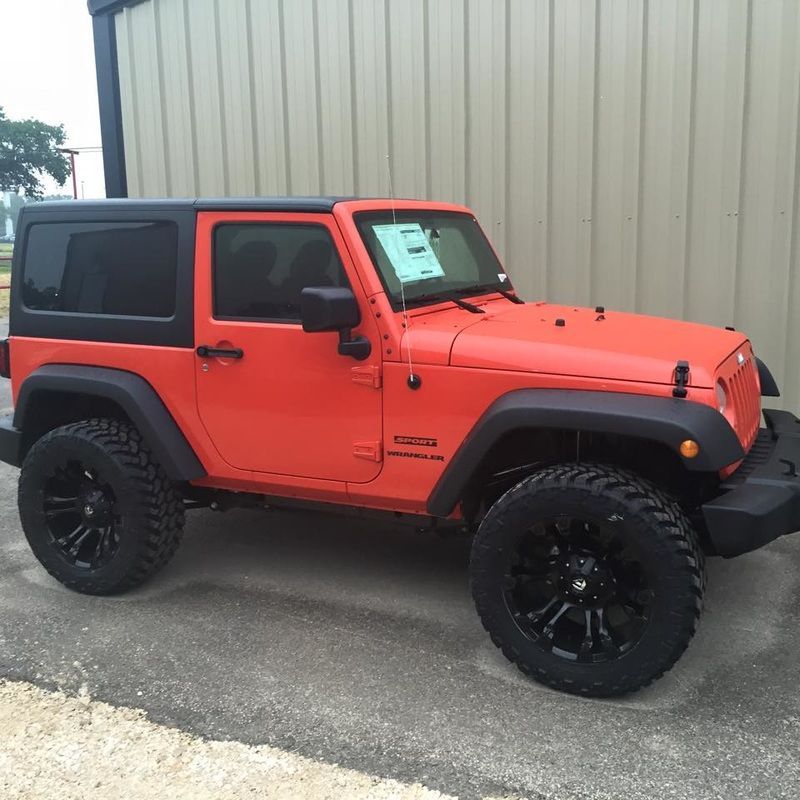 An orange jeep is parked in front of a building