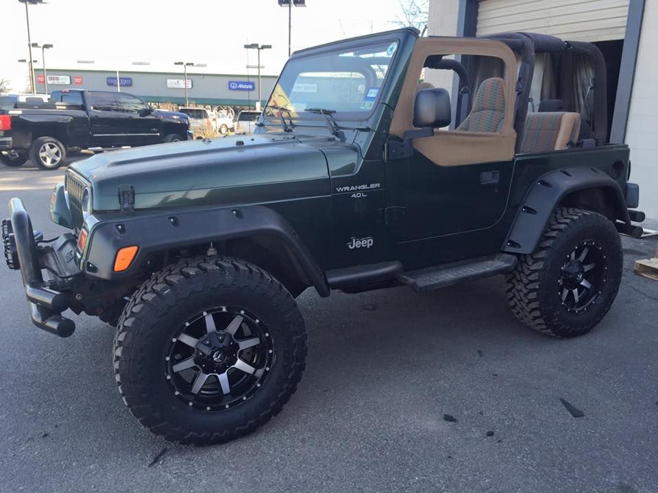 A green jeep is parked in front of a building