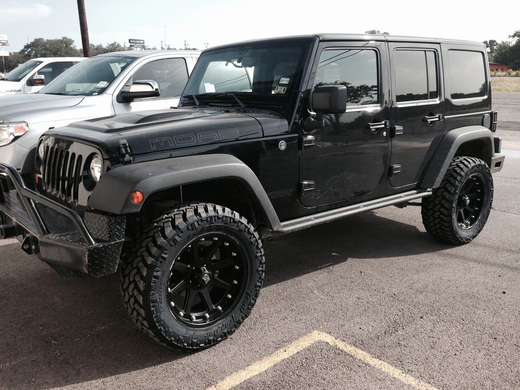 A black jeep is parked in a parking lot.