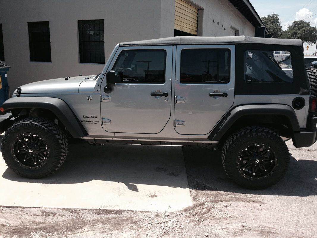 A silver jeep is parked in front of a building