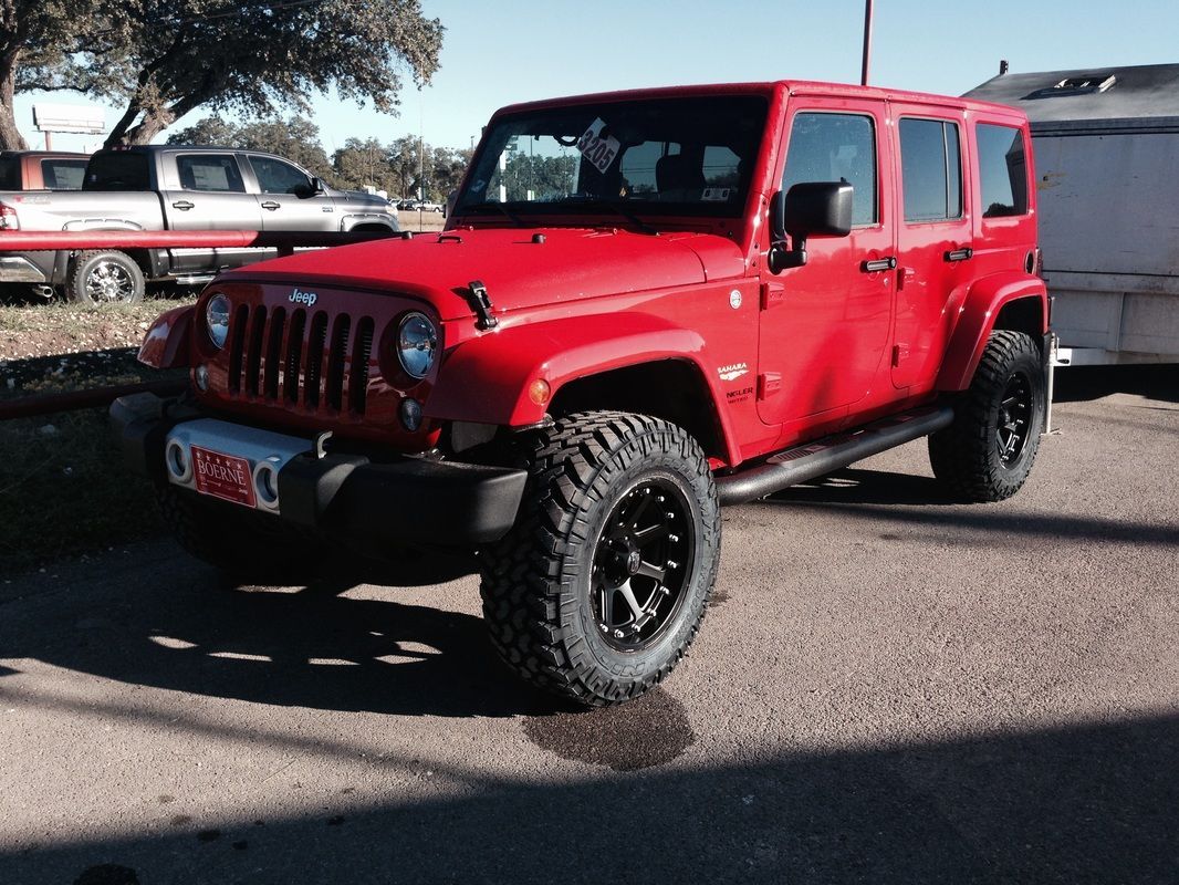 A red jeep is parked in a parking lot
