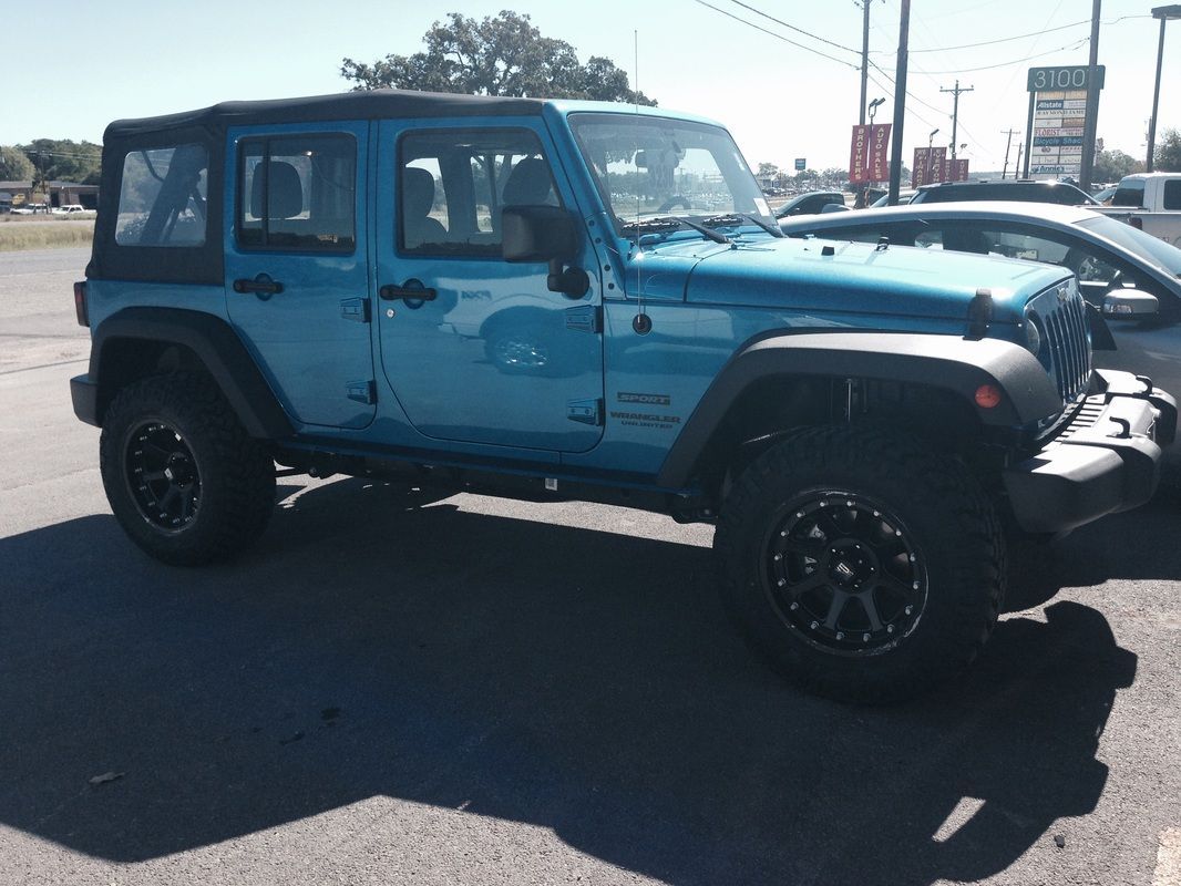 A blue jeep is parked in a parking lot