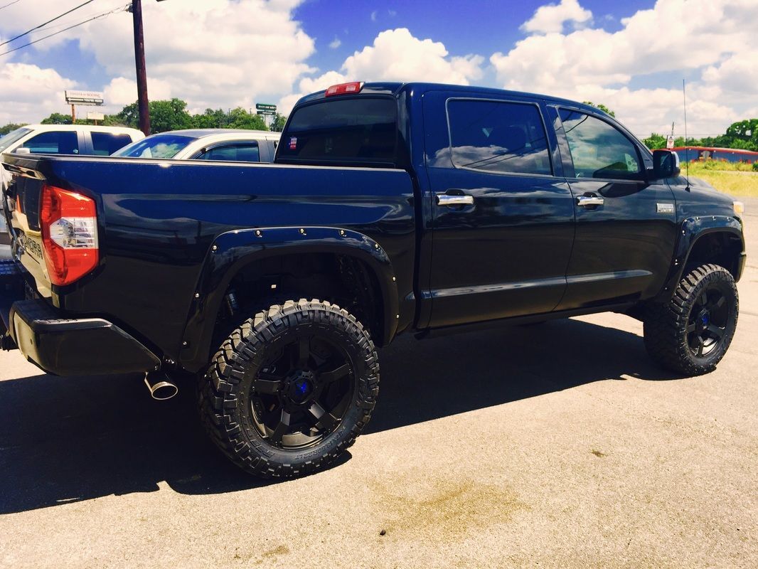 A black truck is parked on the side of the road.