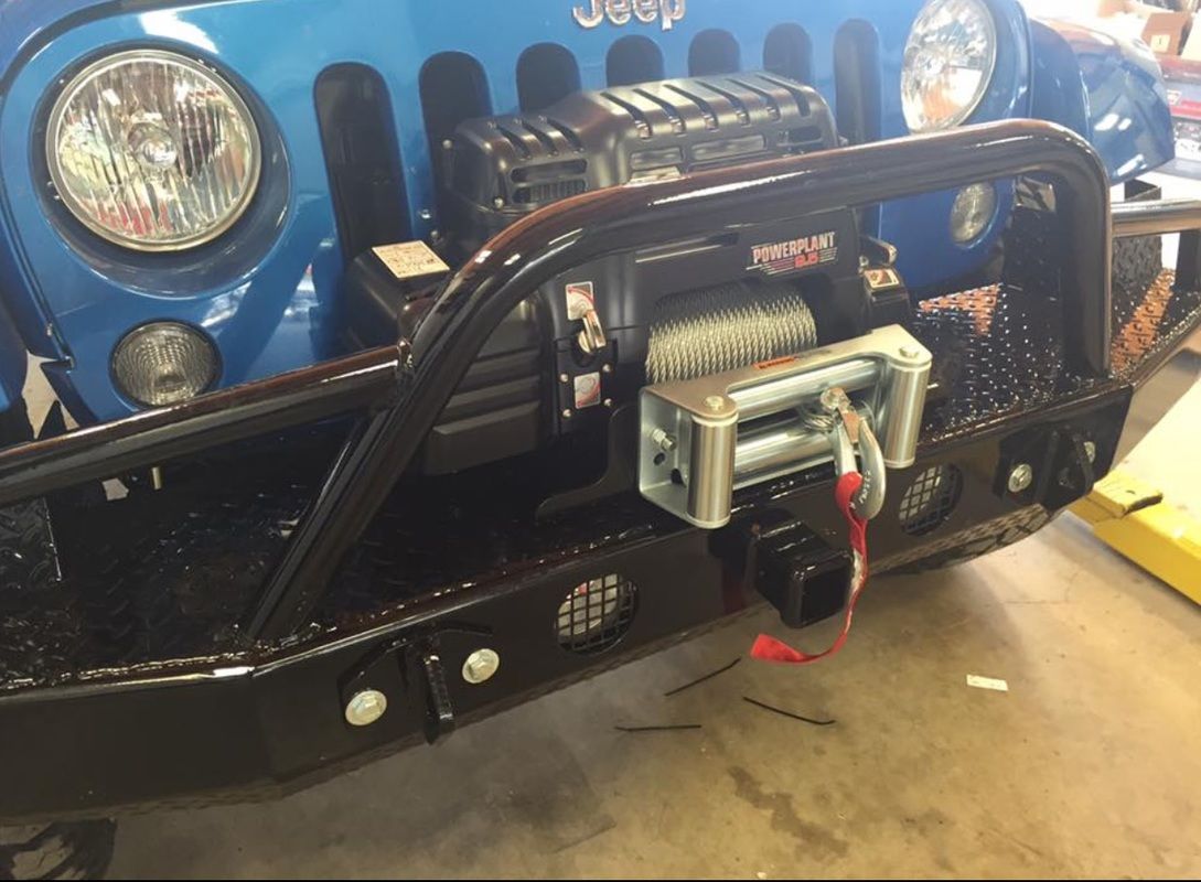 A blue jeep with a winch attached to the front bumper