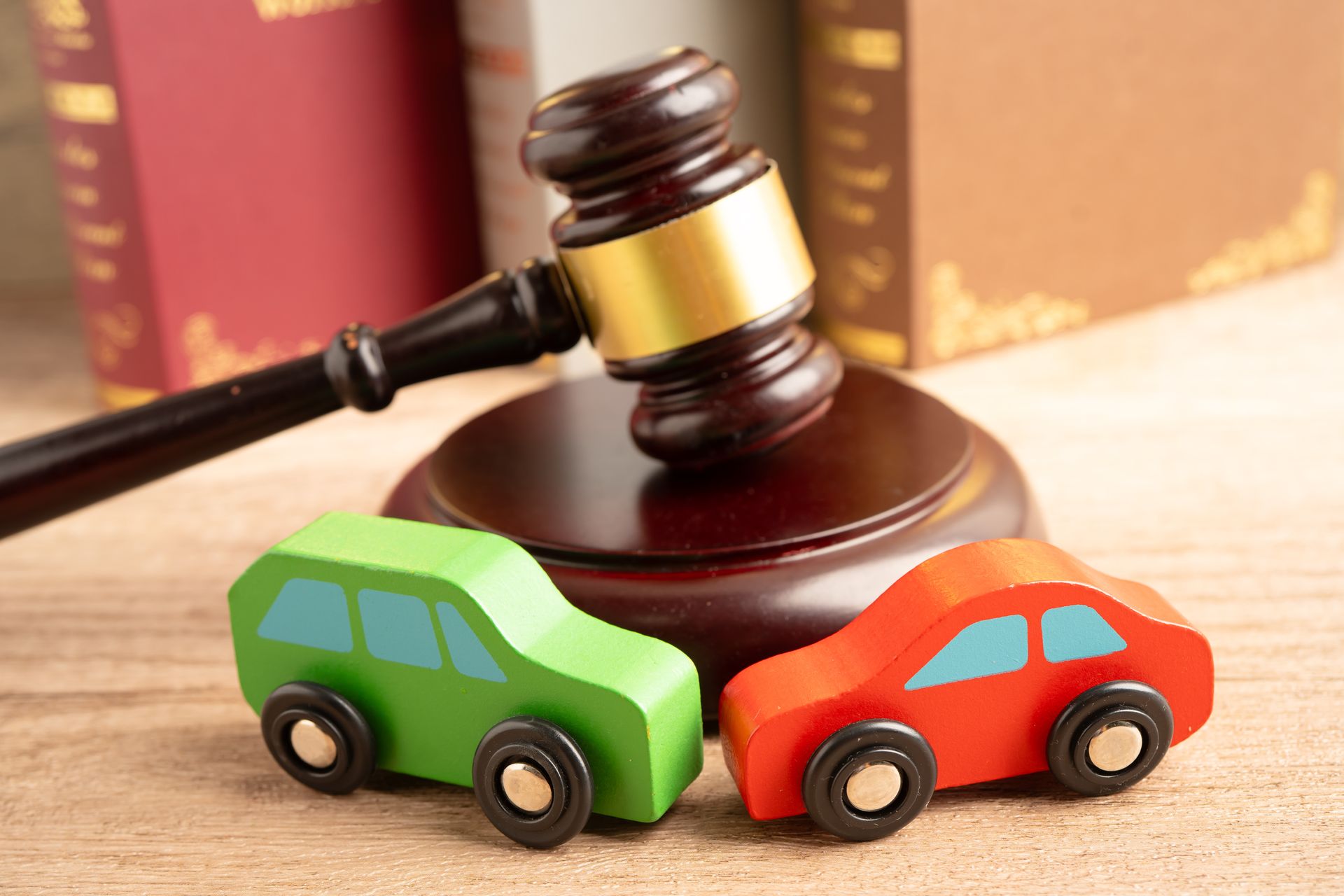 Car accident attorney concept with wooden toy cars beside a judgeās gavel and law books. Car accident attorney concept with wooden toy cars beside a judgeās gavel and law books.