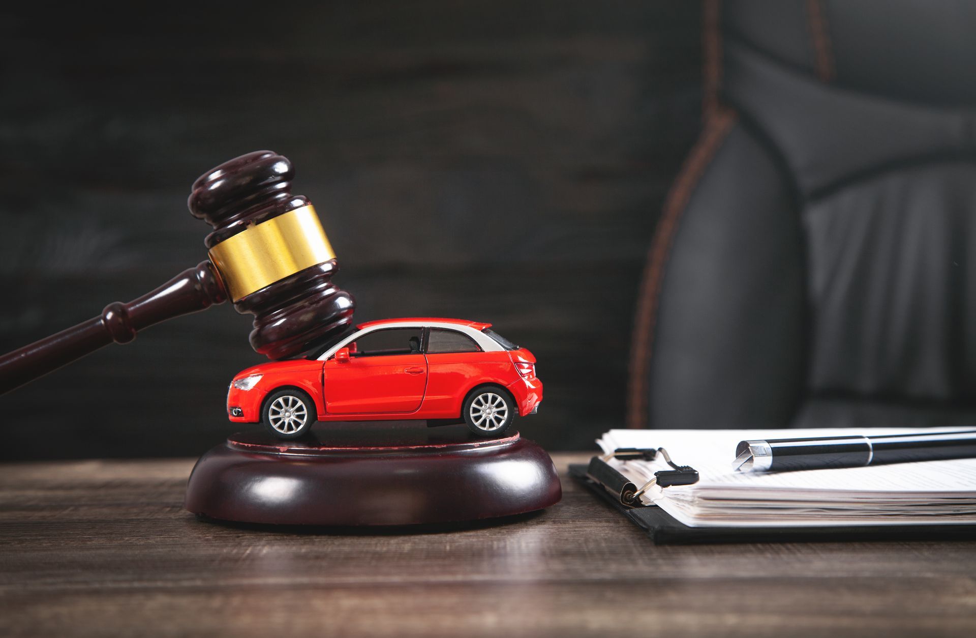 An auto accident attorney is symbolized by a gavel next to a red toy car and legal documents.