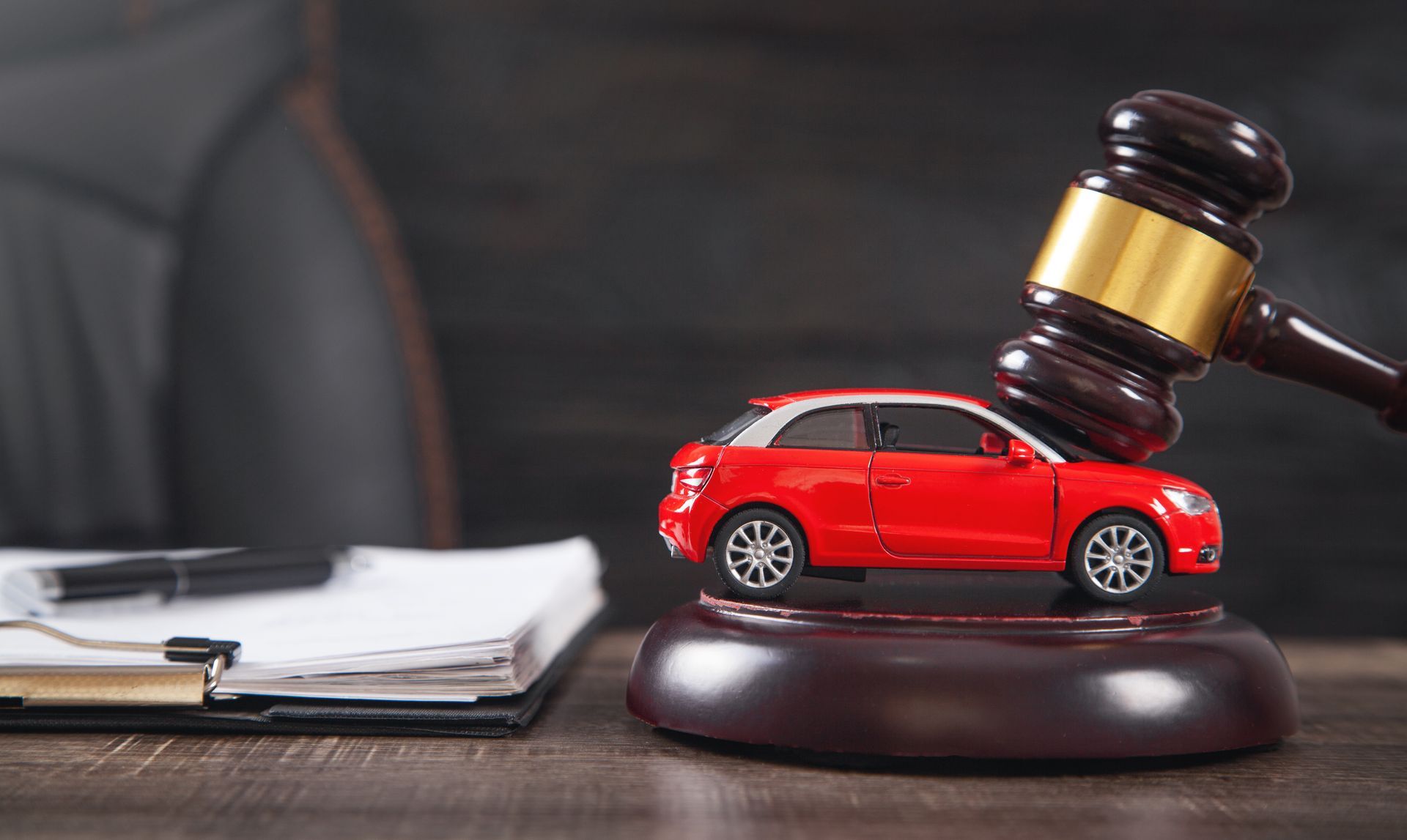 A gavel striking beside a red toy car on a desk symbolizes a car accident case and legal action.