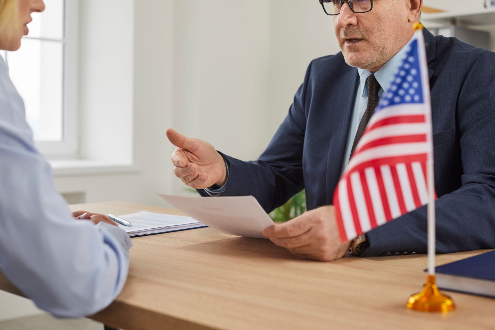A visa application lawyer discussing case details at an office desk. A visa application lawyer discussing case details at an office desk.