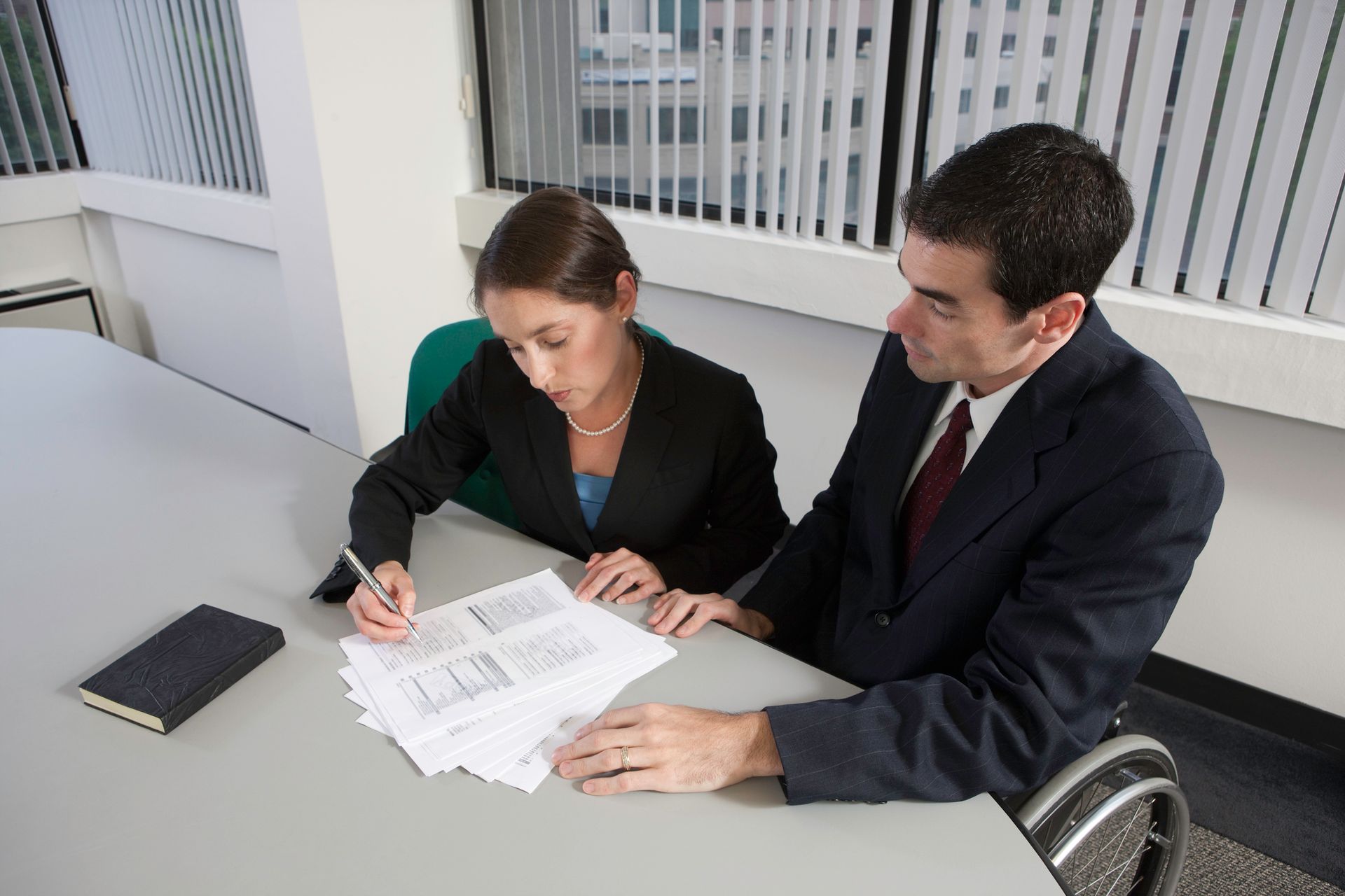 Handicapped businessman signs a document with the help of a personal injury attorney.