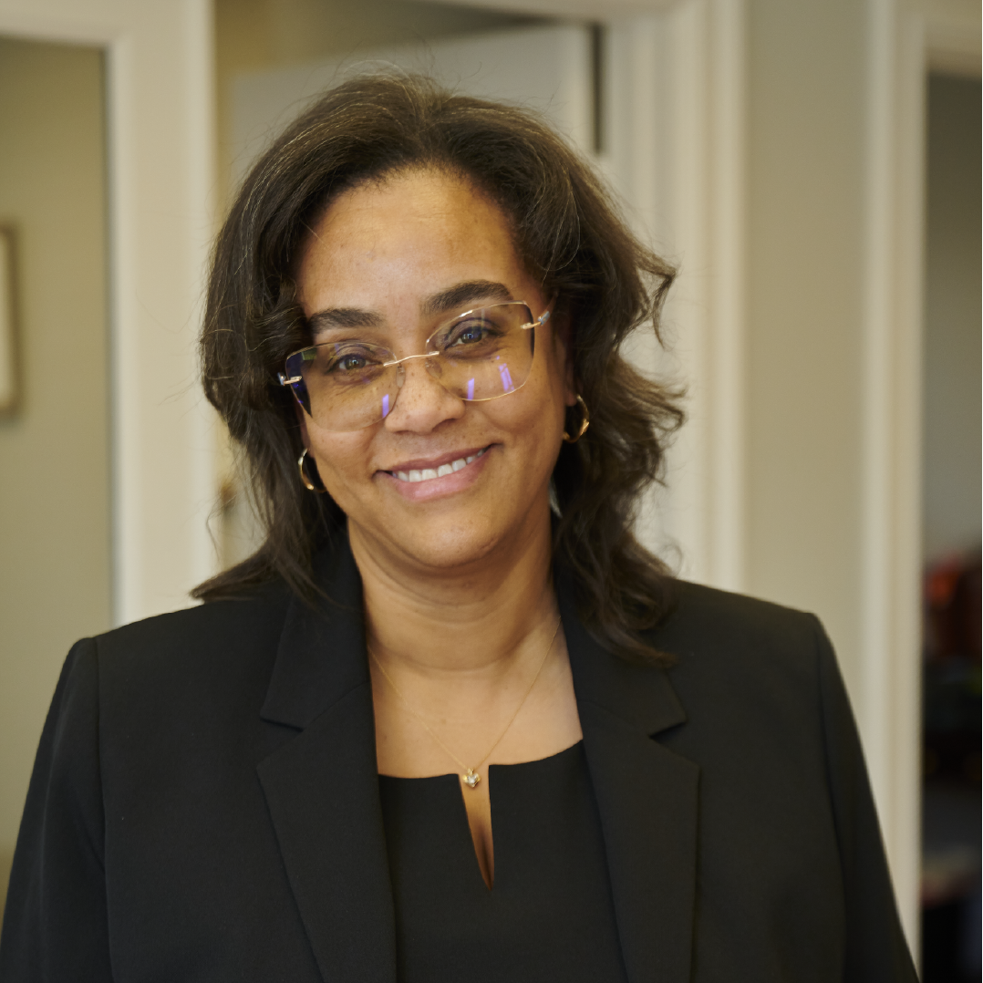 A woman wearing glasses and a black jacket smiles for the camera