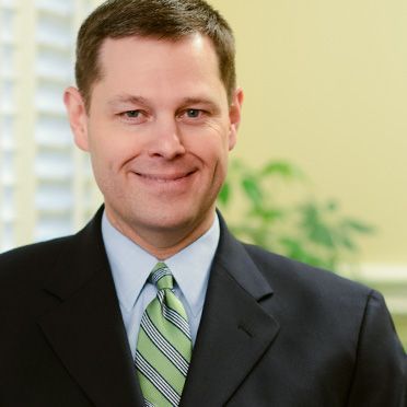 A man in a suit and tie smiles for the camera