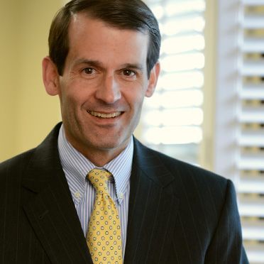 A man in a suit and tie is smiling for the camera