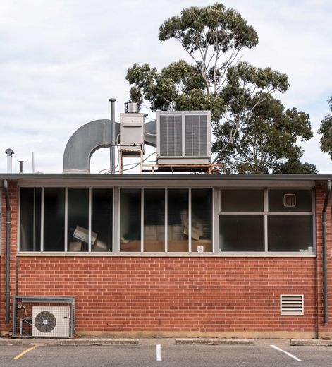 A brick building with a lot of windows and an air conditioner on top of it.