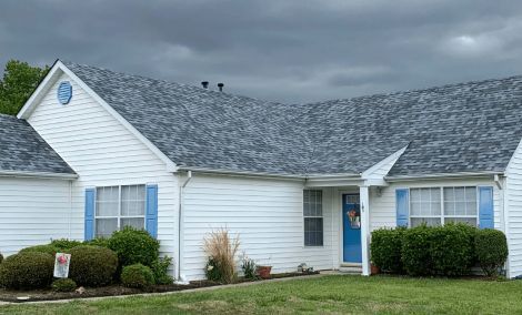 A white house with blue shutters and a gray roof.