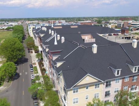 An aerial view of a large apartment building with a black roof