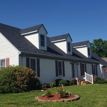 A white house with a black roof and red shutters