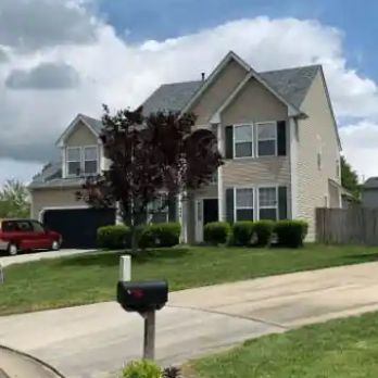 A large house with a red car parked in front of it.