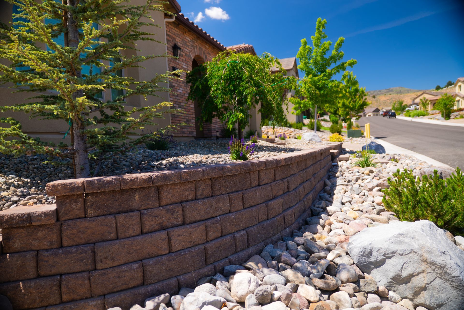 Brick pathway leading to a home's front door, with steps, landscaping, and a blue window.
