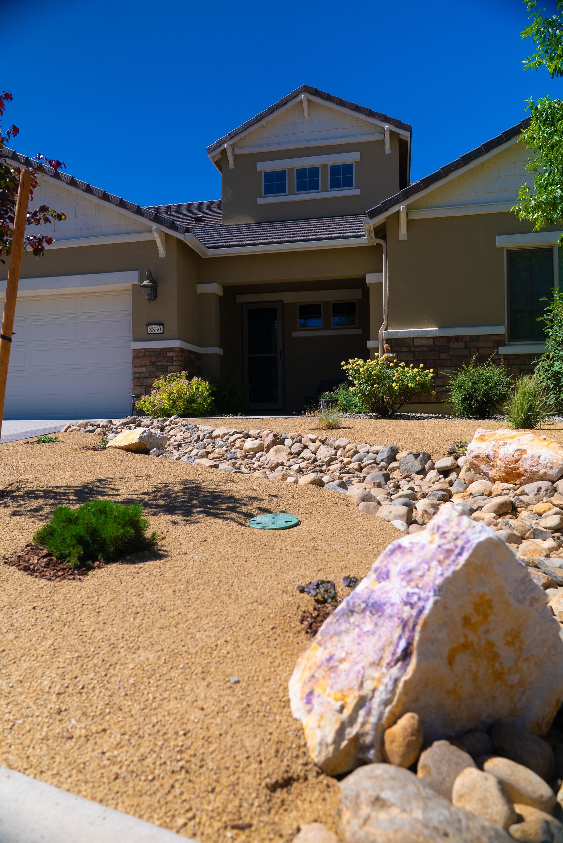 Brick pathway leading to a home's front door, with steps, landscaping, and a blue window.