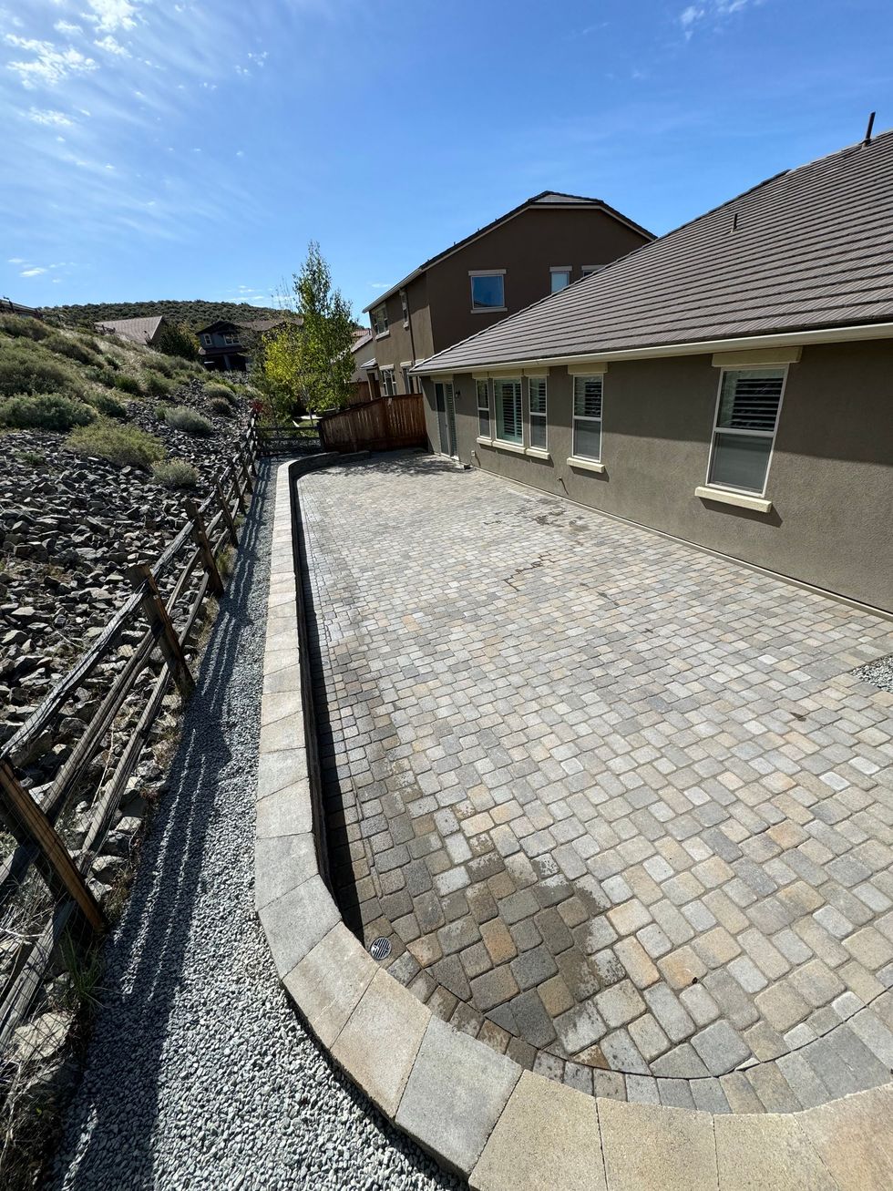 A large house with a hardscaped brick patio.