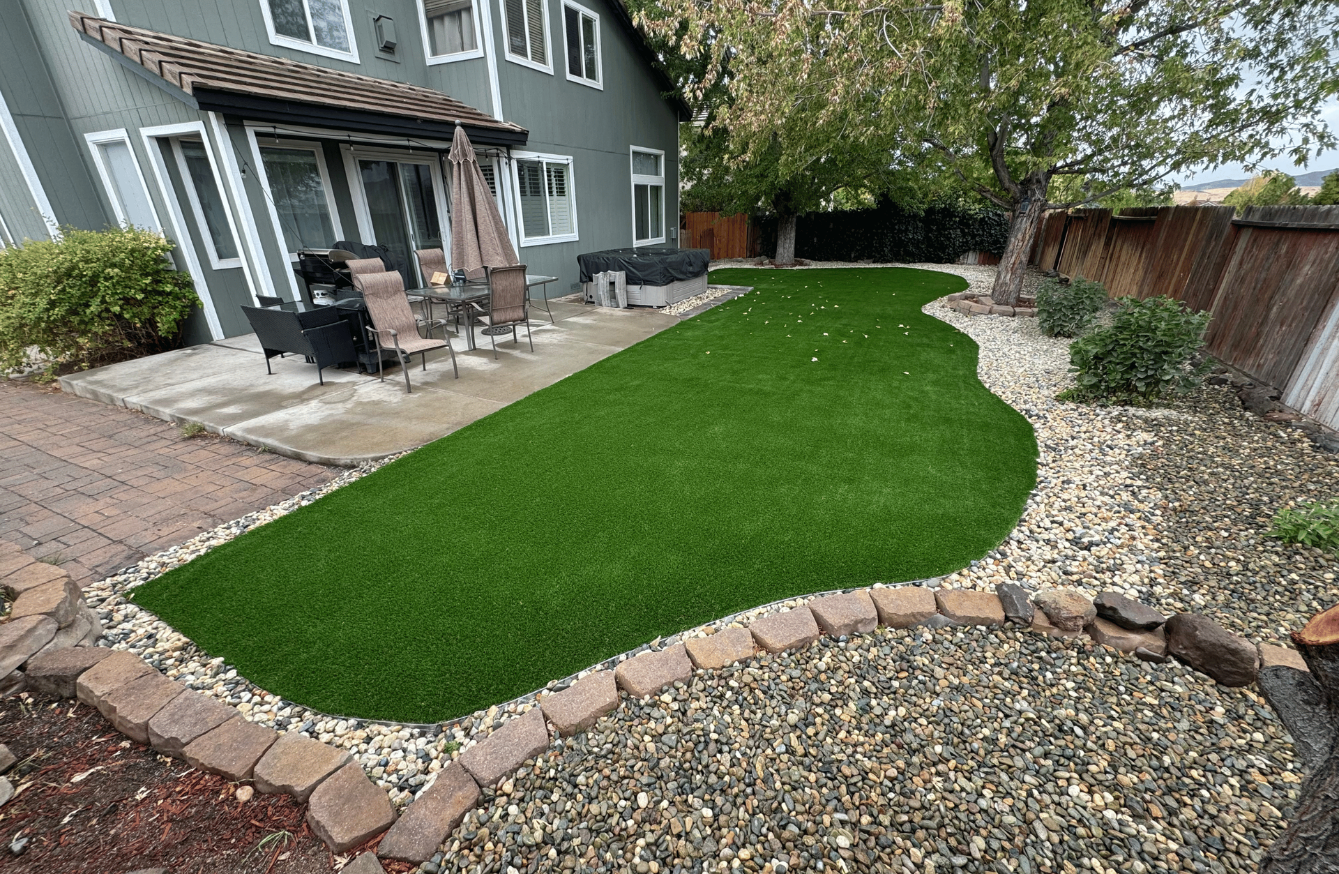A large lush green lawn with trees in the background on a sunny day. designed by All In Hardscape.