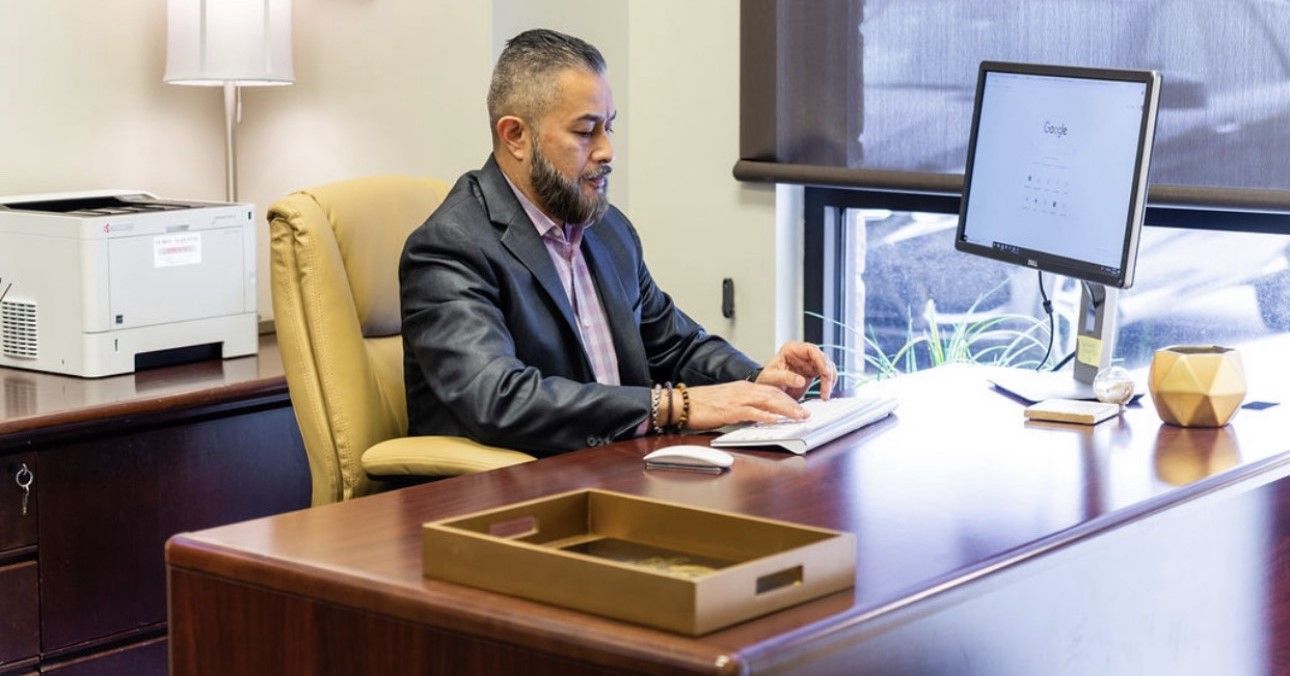 A man is sitting at a desk in front of a computer.