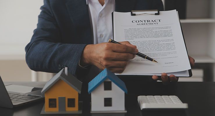 A man is sitting at a desk signing a contract.