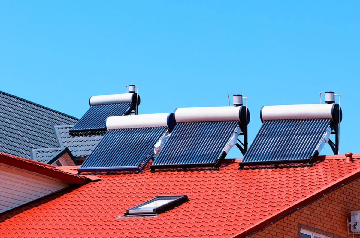Solar Water Heaters on a Red Roof Against a Blue Sky — Expert Plumbing & Solar Services Bathurst in Kelso, NSW