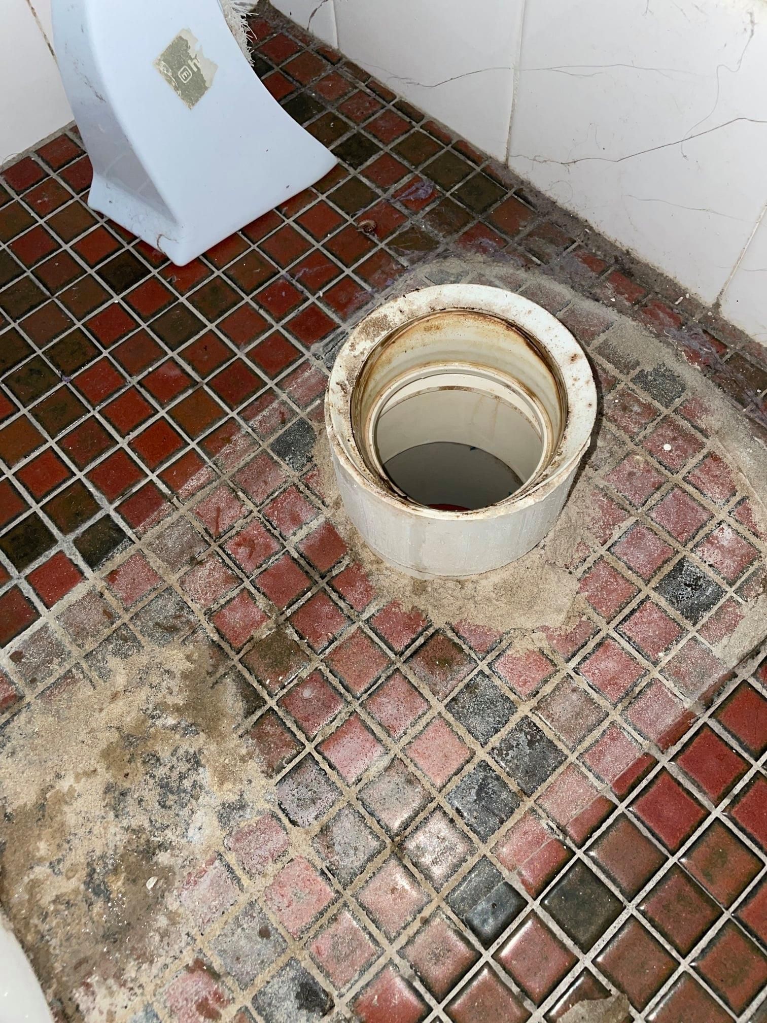 White Toilet Flange in a Red and Black Tiled Bathroom Floor — Expert Plumbing & Solar Services Bathurst in Kelso, NSW