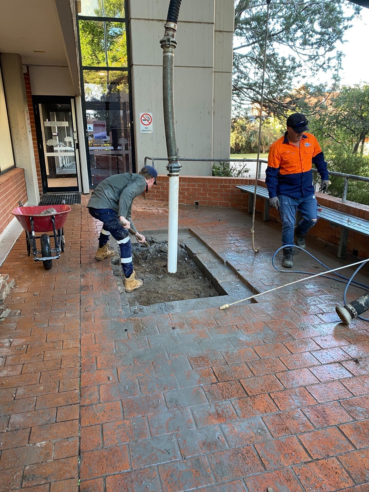 Two Workers Repairing Brick Patio Near Building — Expert Plumbing & Solar Services Bathurst in Kelso, NSW