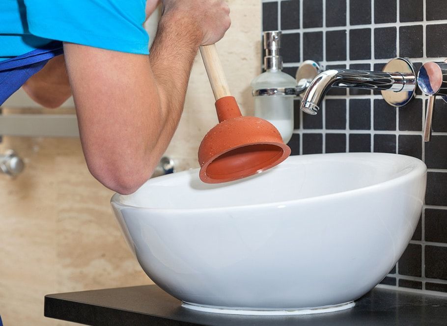 Person Using a Plunger in a White Bathroom Sink — Expert Plumbing & Solar Services Bathurst in Blayney, NSW