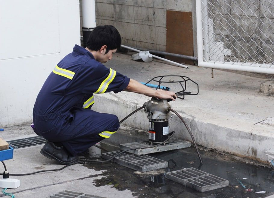 Person in Blue Coveralls Operates Machinery Outdoors Near a Building — Expert Plumbing & Solar Services Bathurst in Kelso, NSW