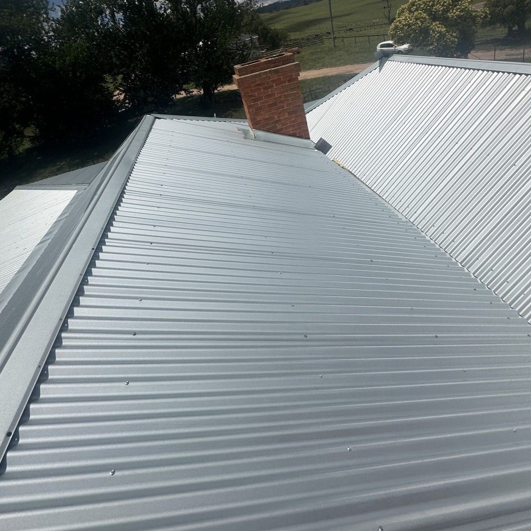Gray Corrugated Metal Roof With a Brick Chimney in a Daytime Outdoor Setting — Expert Plumbing & Solar Services Bathurst in Orange, NSW