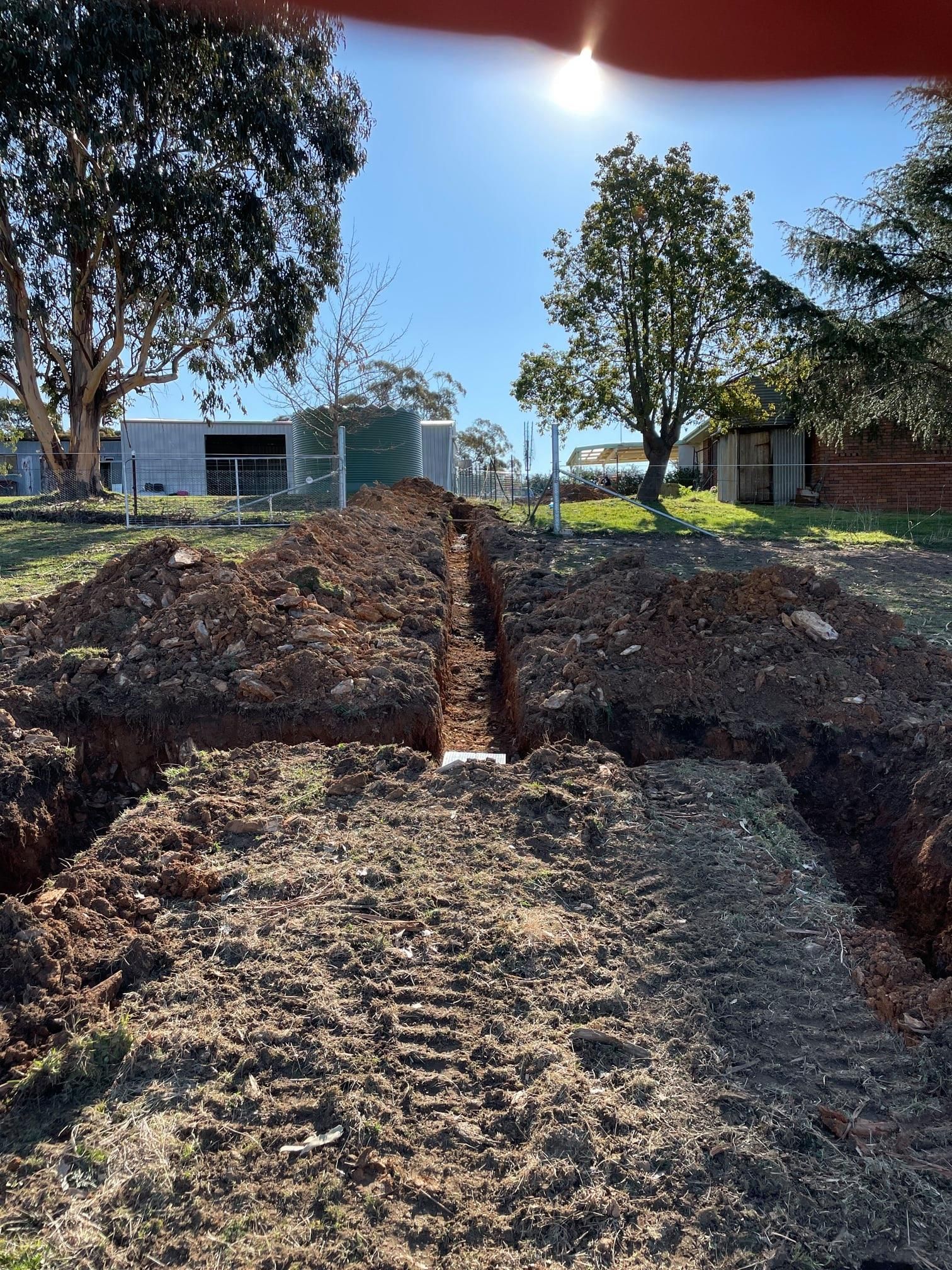 Trench Dug in a Yard, Leading Toward Buildings — Expert Plumbing & Solar Services Bathurst in Orange NSW