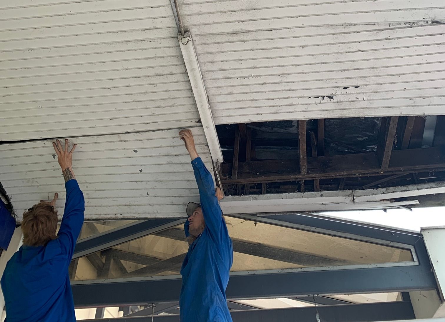Two People in Blue Coveralls Repairing a White — Expert Plumbing & Solar Services Bathurst in Kelso, NSW