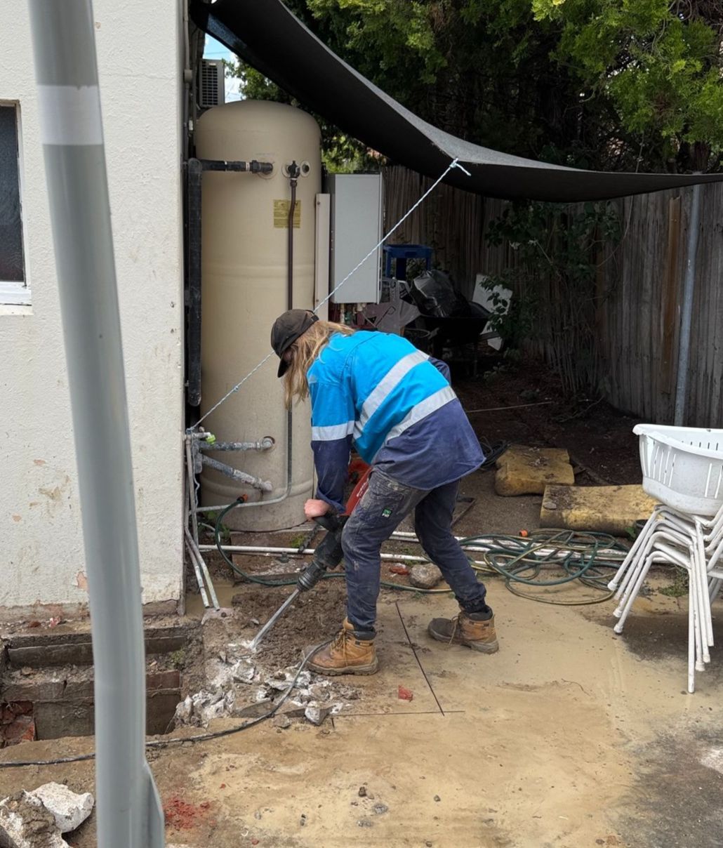 Person Using a Jackhammer Next to a Building — Expert Plumbing & Solar Services Bathurst in Kelso, NSW